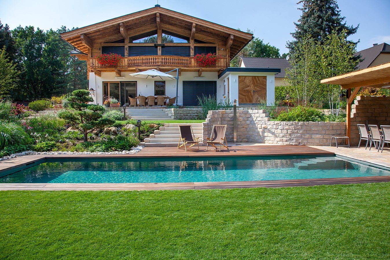 Natuurlijk zwembad met houten randen in de tuin voor een landelijk huis